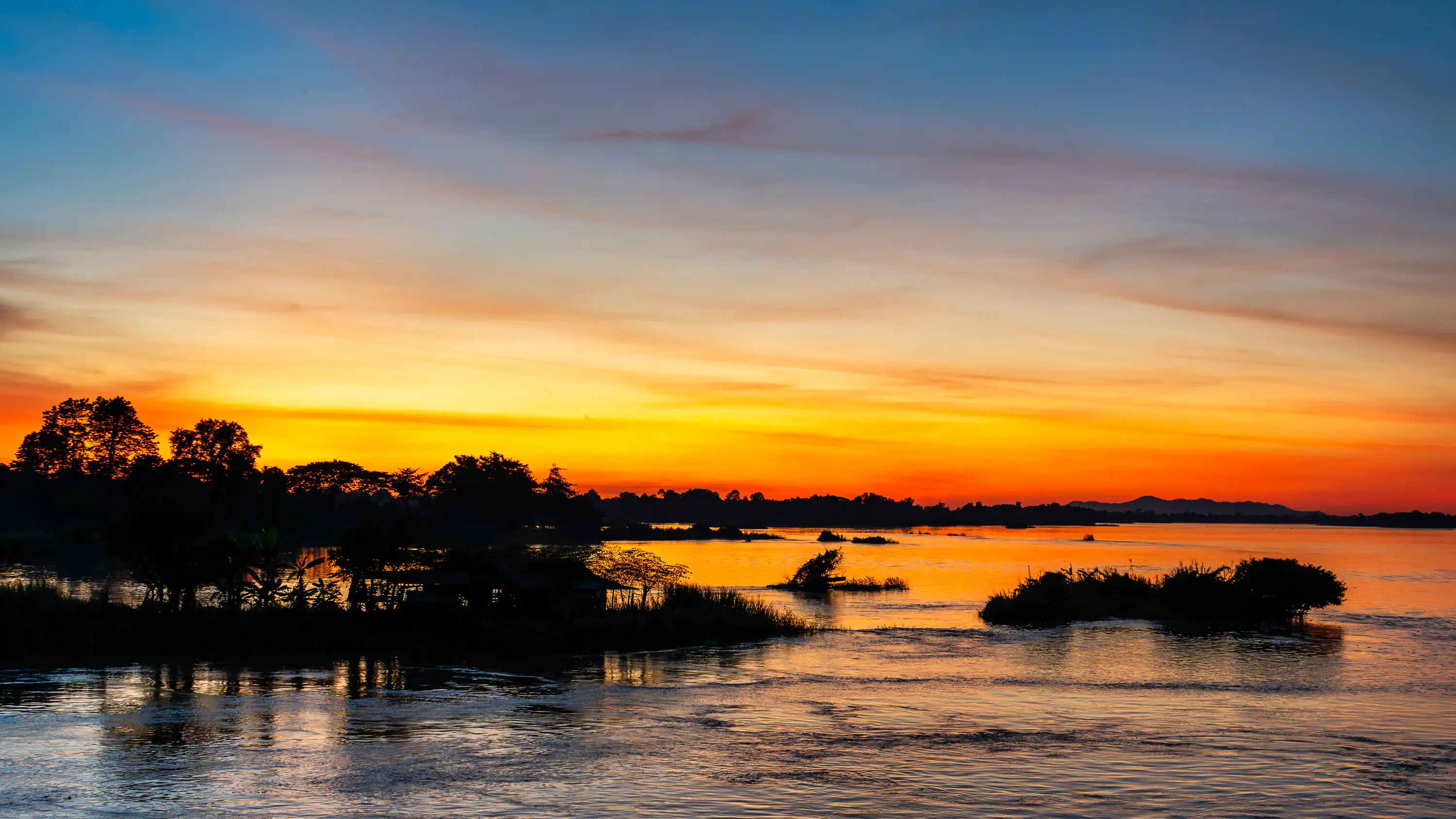 Fiery golden sunset over the Mekong River reflecting vivid colors in Laos.