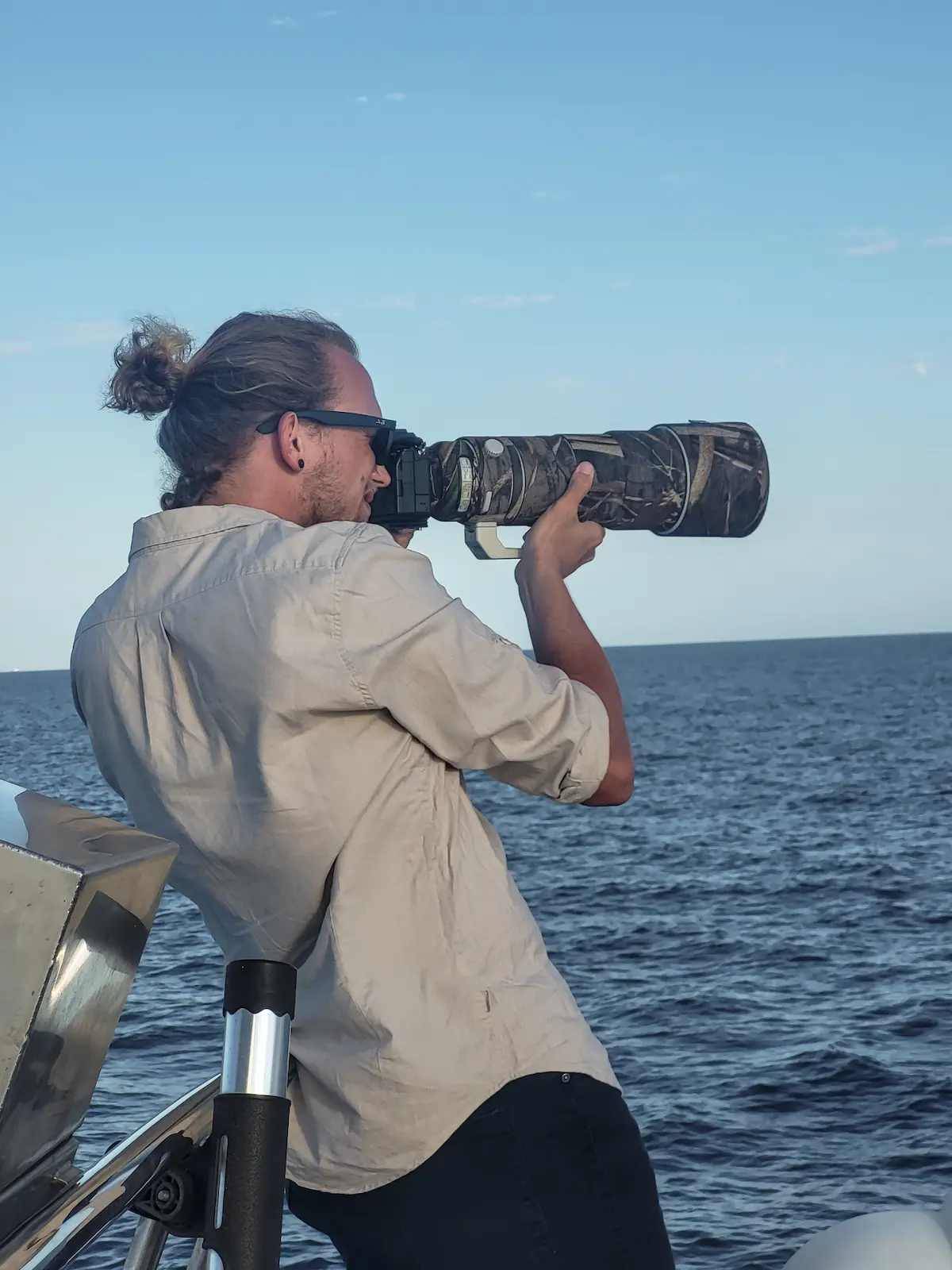Rainer Lentjes ocean photography aiming a telephoto lens toward the horizon while photographing from a boat at sea.